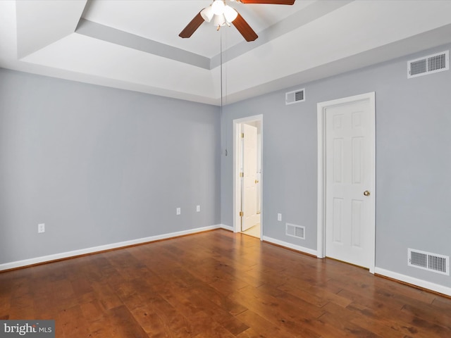 spare room with wood-type flooring, ceiling fan, and a tray ceiling