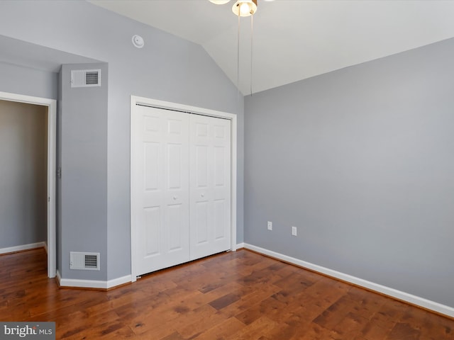 unfurnished bedroom featuring dark wood-type flooring, a closet, and vaulted ceiling