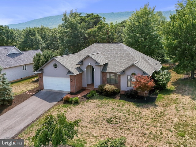 view of front of house with a garage, a front lawn, and a mountain view