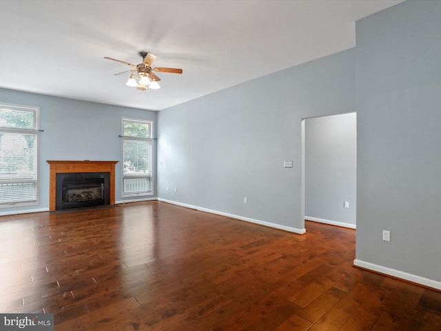 unfurnished living room featuring dark wood-type flooring and ceiling fan