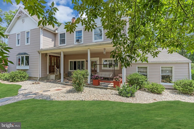 back of house featuring covered porch and a yard