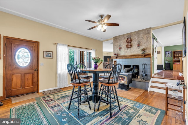 dining area featuring a fireplace, light wood-type flooring, and ceiling fan