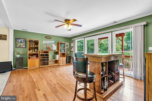 dining space with bar area, light hardwood / wood-style floors, and ceiling fan