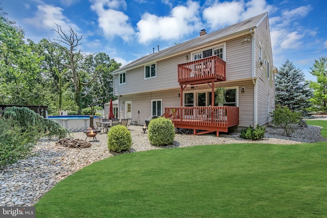 rear view of house featuring a balcony, a swimming pool side deck, and a yard