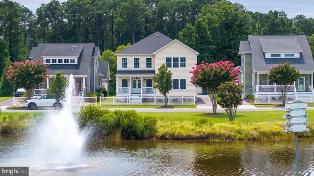 rear view of property featuring a lawn and a water view