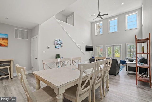 dining room featuring a high ceiling, french doors, ceiling fan, and light wood-type flooring