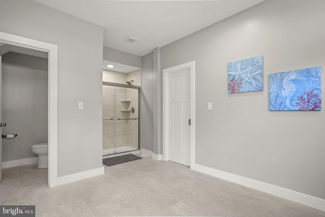 bathroom with tile patterned flooring, a shower with door, and toilet