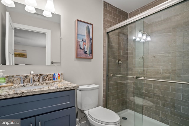 bathroom featuring vanity, a shower with shower door, and toilet