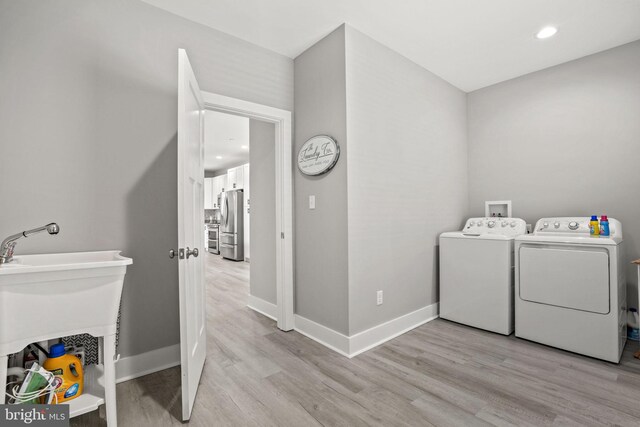 laundry room featuring washer and clothes dryer and light wood-type flooring