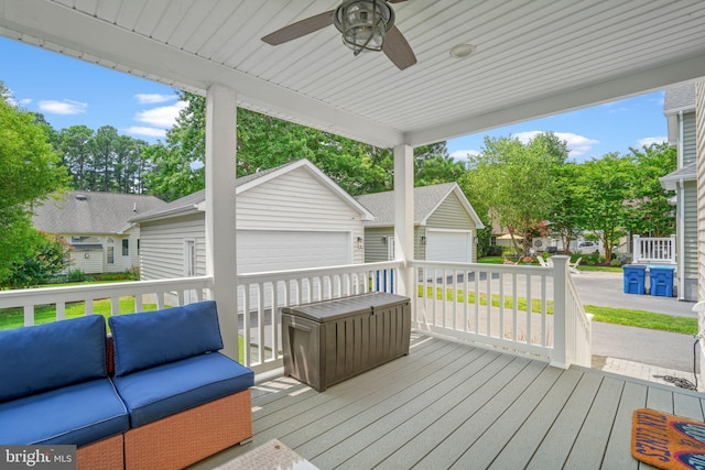 wooden terrace featuring ceiling fan, an outdoor living space, and a garage