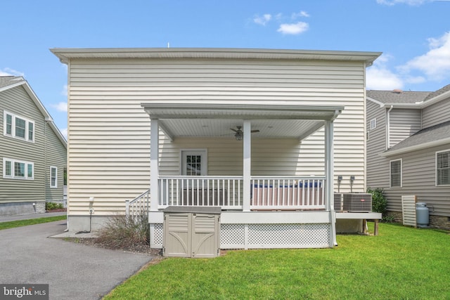 rear view of property with a porch, a lawn, and central air condition unit