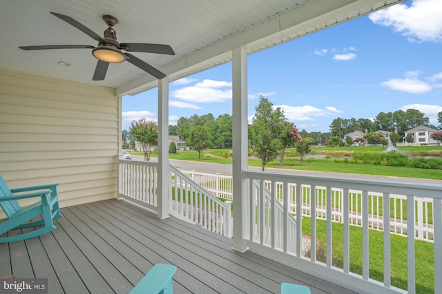 wooden terrace featuring a lawn, ceiling fan, and a porch