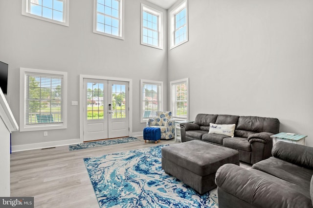 living room featuring hardwood / wood-style flooring, plenty of natural light, french doors, and a high ceiling