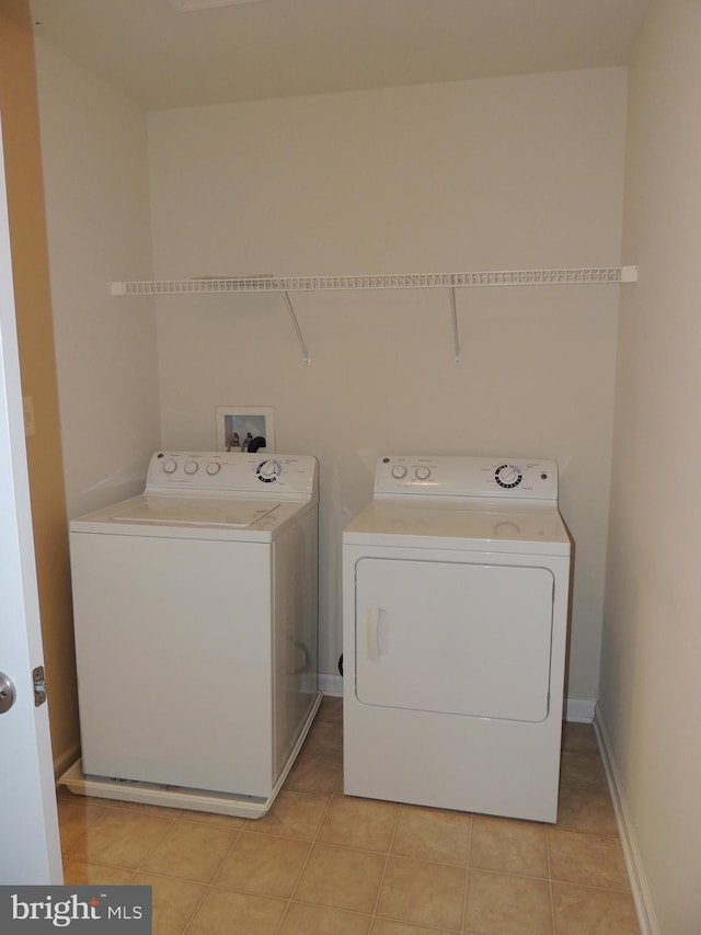 clothes washing area with light tile patterned flooring and washing machine and clothes dryer