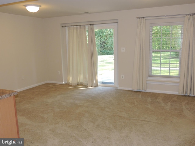 unfurnished room featuring light colored carpet and a healthy amount of sunlight