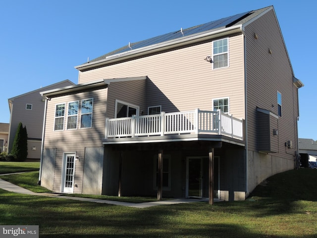 back of property featuring a deck and a lawn