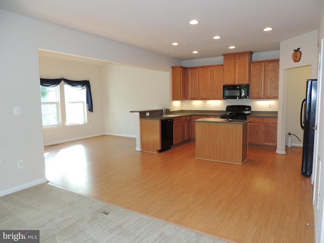 kitchen featuring black appliances, sink, a center island, kitchen peninsula, and light hardwood / wood-style flooring