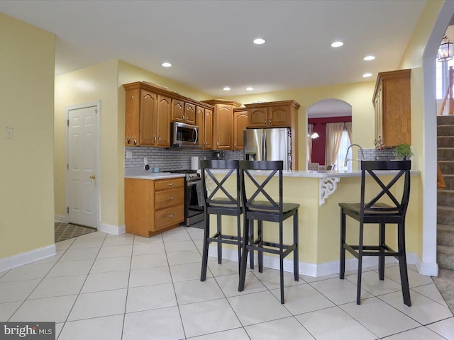 kitchen with tasteful backsplash, a healthy amount of sunlight, appliances with stainless steel finishes, and light tile patterned floors