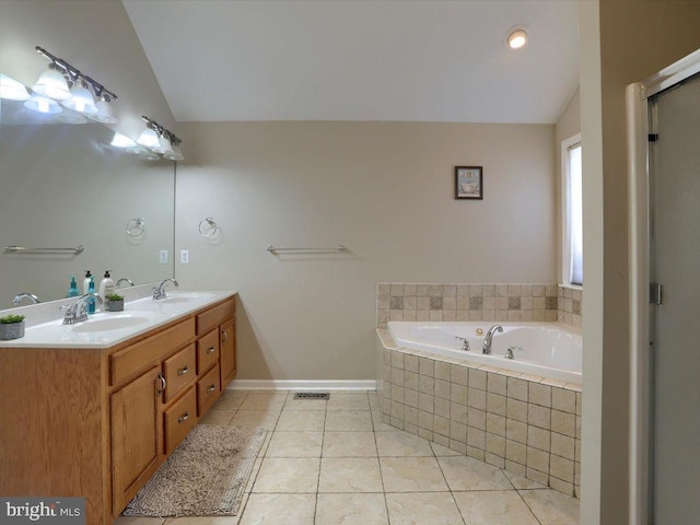 bathroom featuring tiled bath, tile patterned floors, lofted ceiling, and double sink vanity