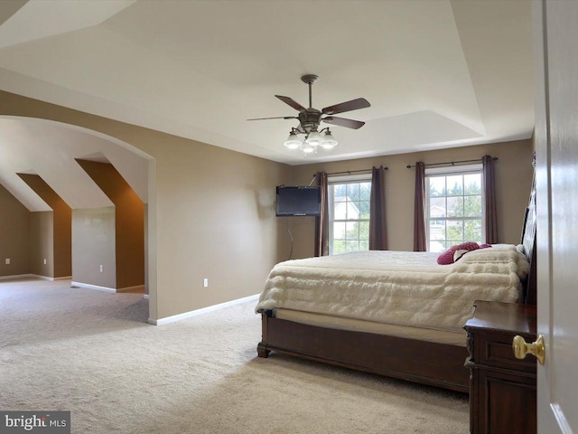 carpeted bedroom with ceiling fan and a raised ceiling