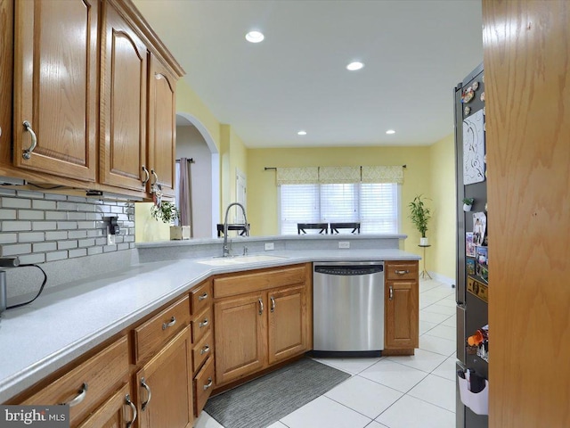 kitchen with appliances with stainless steel finishes, tasteful backsplash, sink, kitchen peninsula, and light tile patterned floors