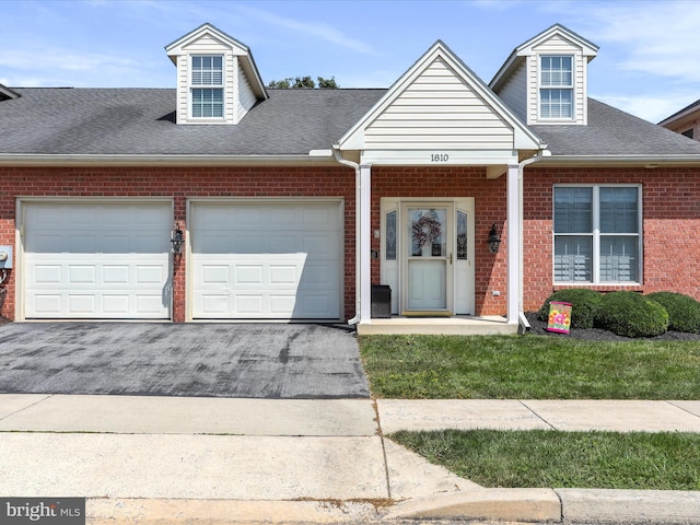 cape cod house with a garage, driveway, a shingled roof, and brick siding