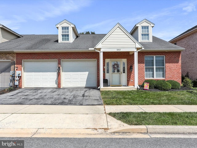 view of front facade featuring aphalt driveway, an attached garage, brick siding, a shingled roof, and fence