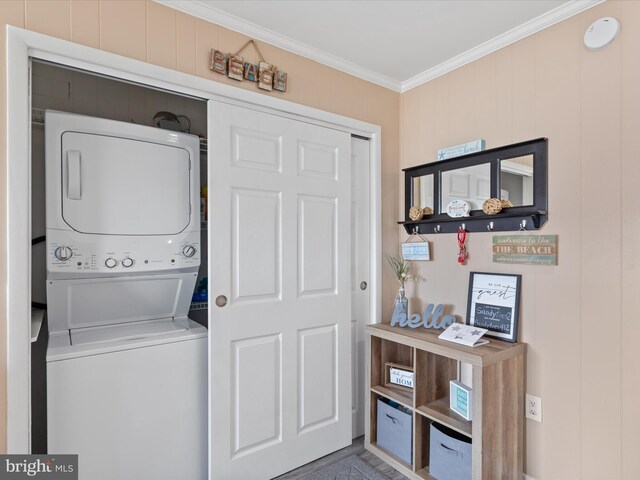 clothes washing area with stacked washer / dryer and ornamental molding