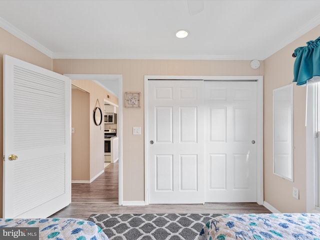 unfurnished bedroom with hardwood / wood-style flooring, crown molding, and a closet