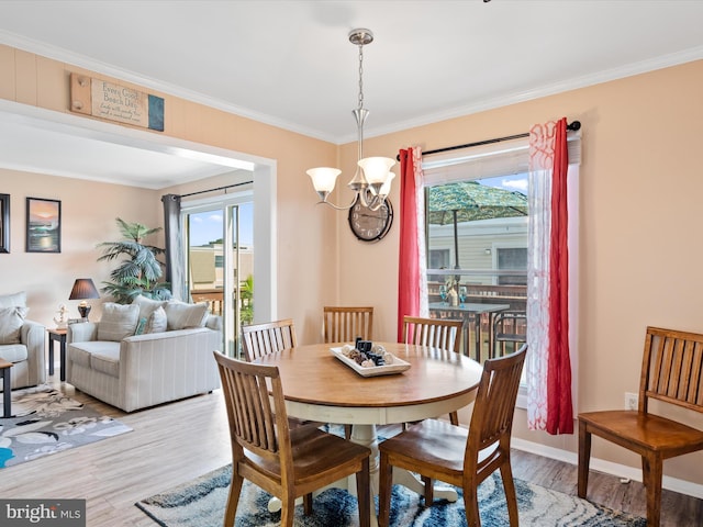 dining space featuring wood-type flooring, ornamental molding, and an inviting chandelier