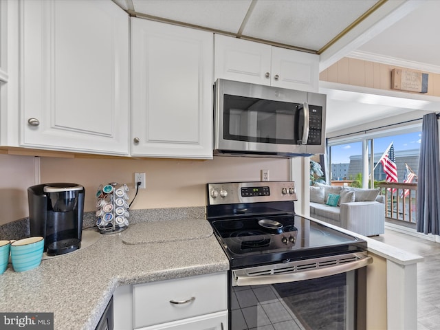 kitchen with ornamental molding, stainless steel appliances, and white cabinets