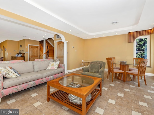 living room featuring decorative columns and a tray ceiling