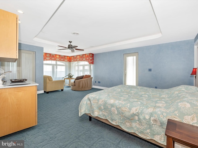 bedroom with a tray ceiling, carpet floors, and ceiling fan