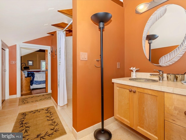 bathroom featuring tile patterned flooring, vaulted ceiling, and vanity