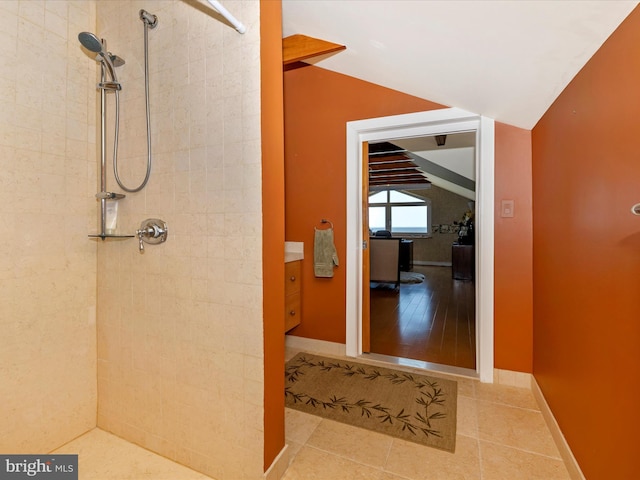 bathroom with tile patterned flooring, vaulted ceiling, and tiled shower