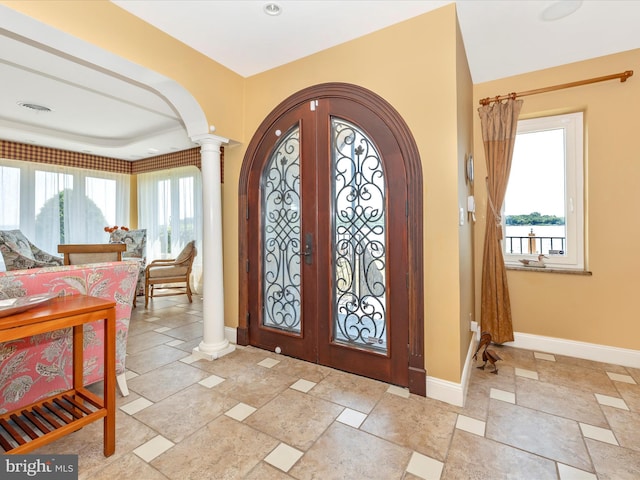 entrance foyer featuring french doors, decorative columns, and a wealth of natural light