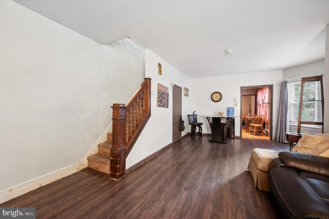 living room featuring dark wood finished floors, baseboards, and stairs