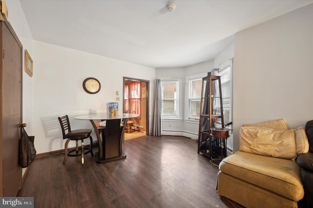 dining room featuring dark wood-style floors, a baseboard heating unit, and baseboards