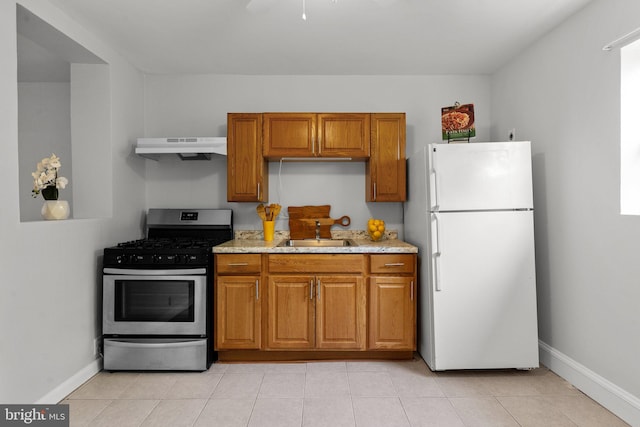 kitchen with sink, light tile patterned floors, gas stove, and white refrigerator