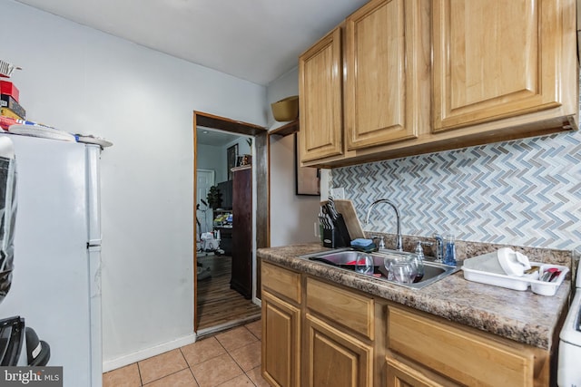 kitchen featuring sink, light tile patterned flooring, white refrigerator, and tasteful backsplash