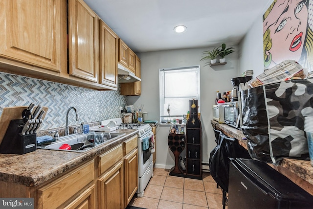 kitchen featuring decorative backsplash, light tile patterned floors, sink, and white gas range