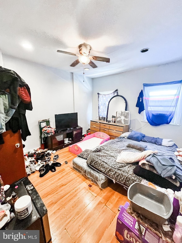 bedroom with a textured ceiling, wood-type flooring, and ceiling fan