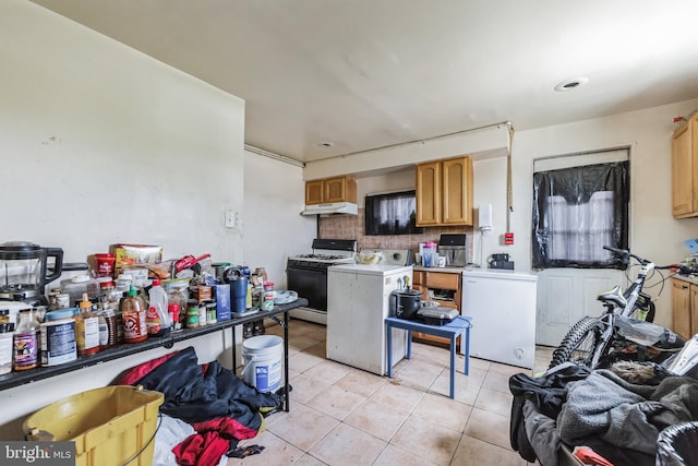 kitchen with fridge, light tile patterned floors, decorative backsplash, and white gas range