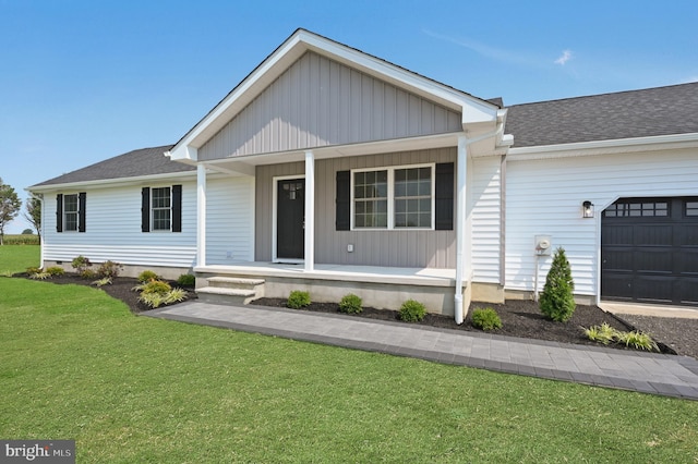 view of front of home with covered porch, a front yard, and a garage