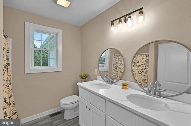 bathroom featuring double sink vanity, toilet, and wood-type flooring