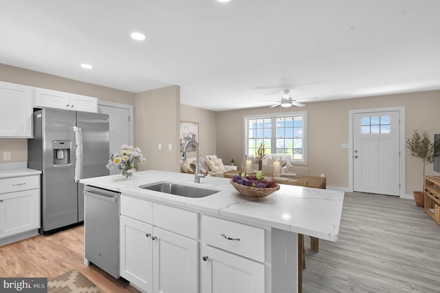 kitchen with ceiling fan, appliances with stainless steel finishes, a center island with sink, light hardwood / wood-style floors, and sink