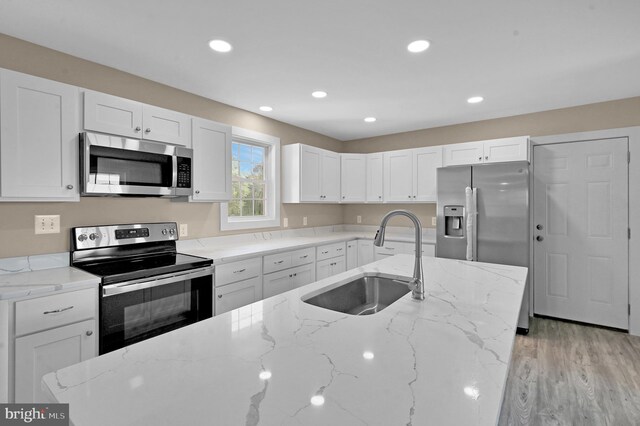 kitchen featuring sink, stainless steel appliances, light hardwood / wood-style floors, and light stone countertops