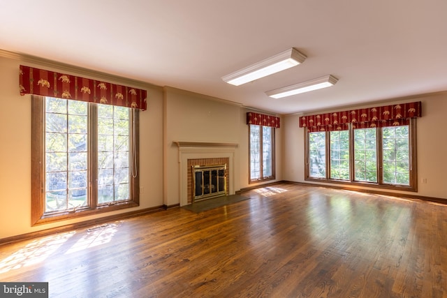 unfurnished living room featuring a brick fireplace, ornamental molding, and hardwood / wood-style floors