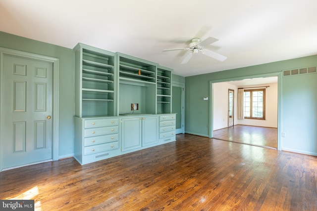 unfurnished living room featuring dark wood-type flooring and ceiling fan