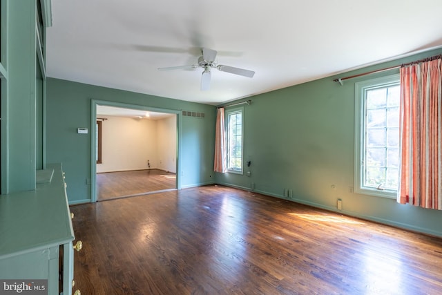 unfurnished room featuring ceiling fan, a healthy amount of sunlight, and dark hardwood / wood-style floors